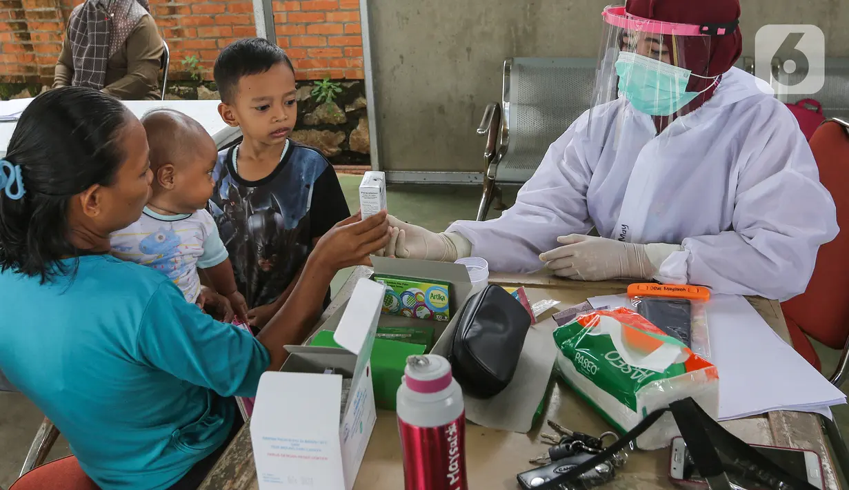 Bidan lengkap dengan baju Alat Pelindung Diri (APD) menjelaskan kegunaan obat kepada warga di Posko Imunisasi, Kelurahan Bakti Jaya, Tangerang Selatan, Senin (11/5/2020). Pada masa pandemi  Covid-19 pemberian vaksin atau imunisasi pada bayi sesuai jadwal. (Liputan6.com/Fery Pradolo)