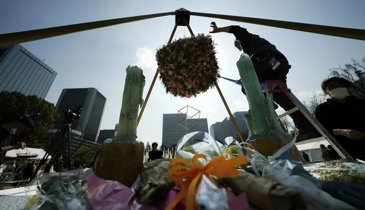 Anggota staf merawat altar darurat untuk berkabung bagi korban gempa bumi dan tsunami 11 Maret 2011 dalam acara peringatan khusus di Tokyo, Jumat (11/3/2022). Jepang menandai peringatan 11 tahun gempa bumi, tsunami dan bencana nuklir yang melanda pantai timur laut Jepang. (AP Photo/Eugene Hoshiko)