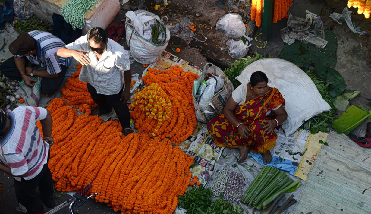 Para pedagang menjajakan bunga untuk dijual selama Festival Durga Puja di pinggir jalan Siliguri, India, Selasa (12/10/2021). Durga Puja juga disebut Durgotsab adalah festival tahunan di Asia Selatan untuk memuja dewi Durga dari agama Hindu. (DIPTENDU DUTTA/AFP)