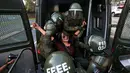 Seorang wanita dimasukan ke dalam mobil polisi anti huru hara saat melakukan demonstrasi di luar kedutaan AS di Santiago, Chili (14/4). (AP / Esteban Felix)