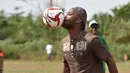 Mantan penyerang Chelsea, Didier Drogba berusaha mengontrol bola saat bermain dengan murid-murid saat peresmian sekolah di Pokou-Kouamekro, dekat Gagnoa, Pantai Gading tengah barat (17/1). (AFP Photo/Sia Kambou)