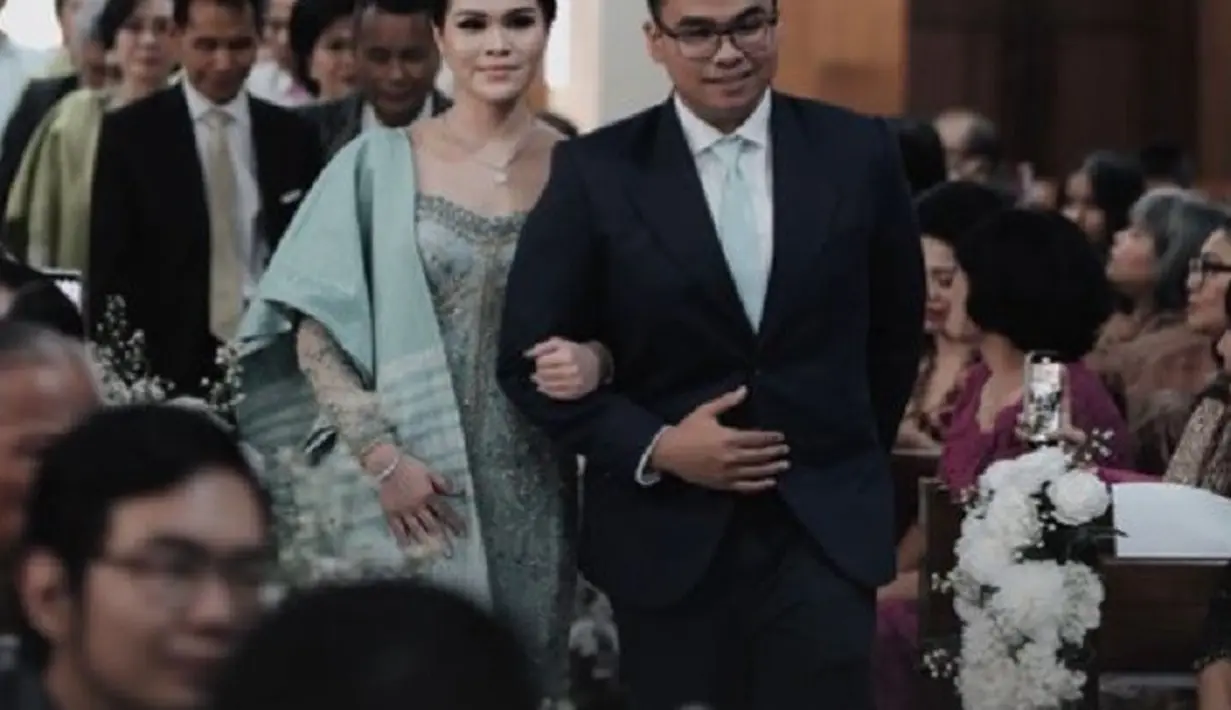 Penampilan Fritz Hutapea di acara pertunangan adat Batak ini, dikombinasikan dengan kemeja putih dan dasi biru muda yang serasi. [Foto: Instagram/harvestdecoration]