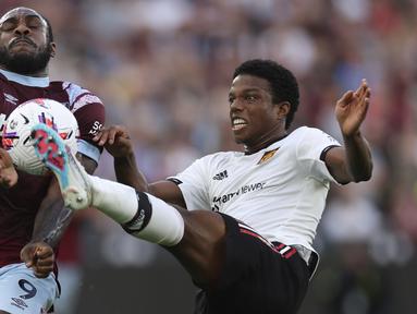 Pemain West Ham, Michail Antonio (kiri), berusaha mengontrol bola dan melewati pemain MU, Tyrell Malacia, dalam laga pekan ke-35 Premier League 2022/2023 yang berlangsung di London Stadium, Senin (8/5/2023) dini hari. (AP Photo/Ian Walton)