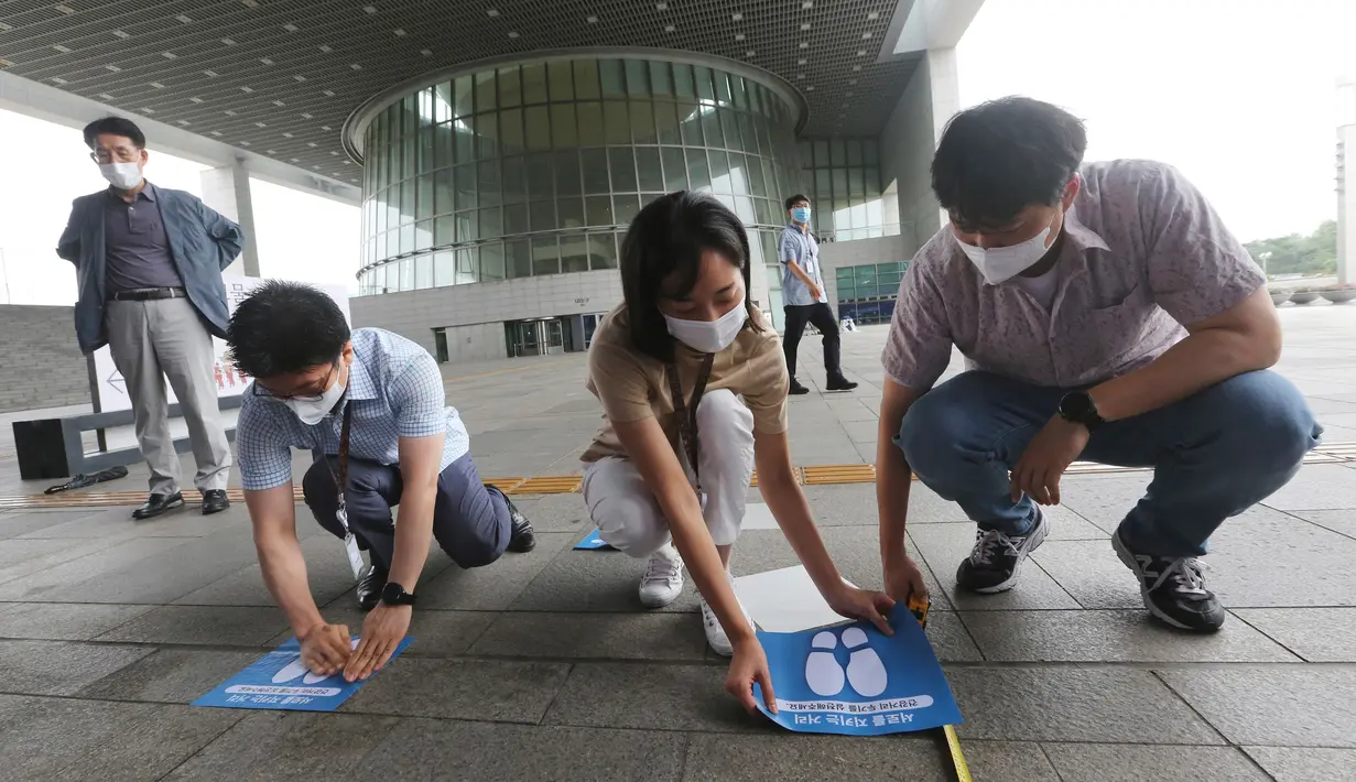 Para pekerja menempelkan tanda-tanda jarak sosial di lantai Museum Nasional Korea di Seoul, Korea Selatan, Rabu (22/7/2020). Museum ini dibuka kembali pada Rabu (22/7) setelah ditutup selama dua bulan akibat pandemi corona Covid-19. (AP Photo/Ahn Young-joon)