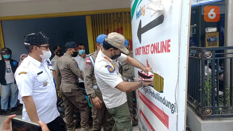 Satpol PP Banyuwangi membongkar banner rapid tes antigen ilegal di Kawasan Pelabuhan Ketapang Banyuwangi. (Hermawan Arifianto/Liputan6.com)