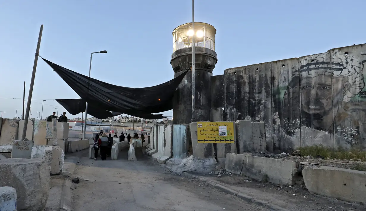 Anggota pasukan keamanan Israel berjaga-jaga di pos pemeriksaan Qalandia antara kota Ramallah Tepi Barat dan Yerusalem, ketika orang-orang Palestina menyeberang untuk menghadiri sholat Jumat kedua bulan Ramadhan di masjid Al-Aqsa, Jumat (23/4/2021). (ABBAS MOMANI / AFP)