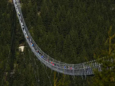 Pengunjung melintasi jembatan gantung untuk pejalan kaki yang merupakan konstruksi terpanjang di dunia setelah pembukaan resminya di sebuah resor pegunungan di Dolni Morava, Republik Ceko, Jumat (13/5/2022). Jembatan sepanjang 721 meter (2.365 kaki) dibangun pada ketinggian lebih dari 1.100 meter di atas permukaan laut. (AP Photo/Petr David Josek)