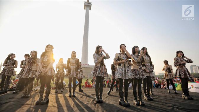 Aksi para personel girlband JKT48 saat tampil dalam puncak Kirab Obor Asian Games 2018 di Monas, Jakarta, Sabtu (18/8). Obor Asian Games 2018 diarak dari Monumen Nasional (Monas) menuju Stadion Utama Gelora Bung Karno (SUGBK). (Liputan6.com/Faizal Fanani)