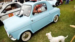 Dua pengunjung saat berada di dalam Sebuah mobil Vespa 1960 saat dipamerkan di Concours d'LeMons, Seaside, California, AS, (20/8). Para pengunjung dibuat terpana dengan Mobil antik yang dipamerkan dan ingin memilikinya. (Reuters/Michael Fiala)