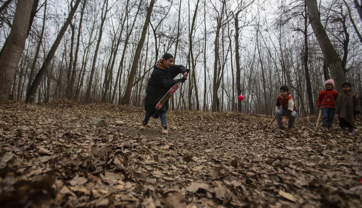 Anak laki-laki Kashmir bermain kriket pada hari yang dingin di pinggiran Srinagar, Kashmir yang dikuasai India, Senin (27/12/2021). (AP Photo/Mukhtar Khan)