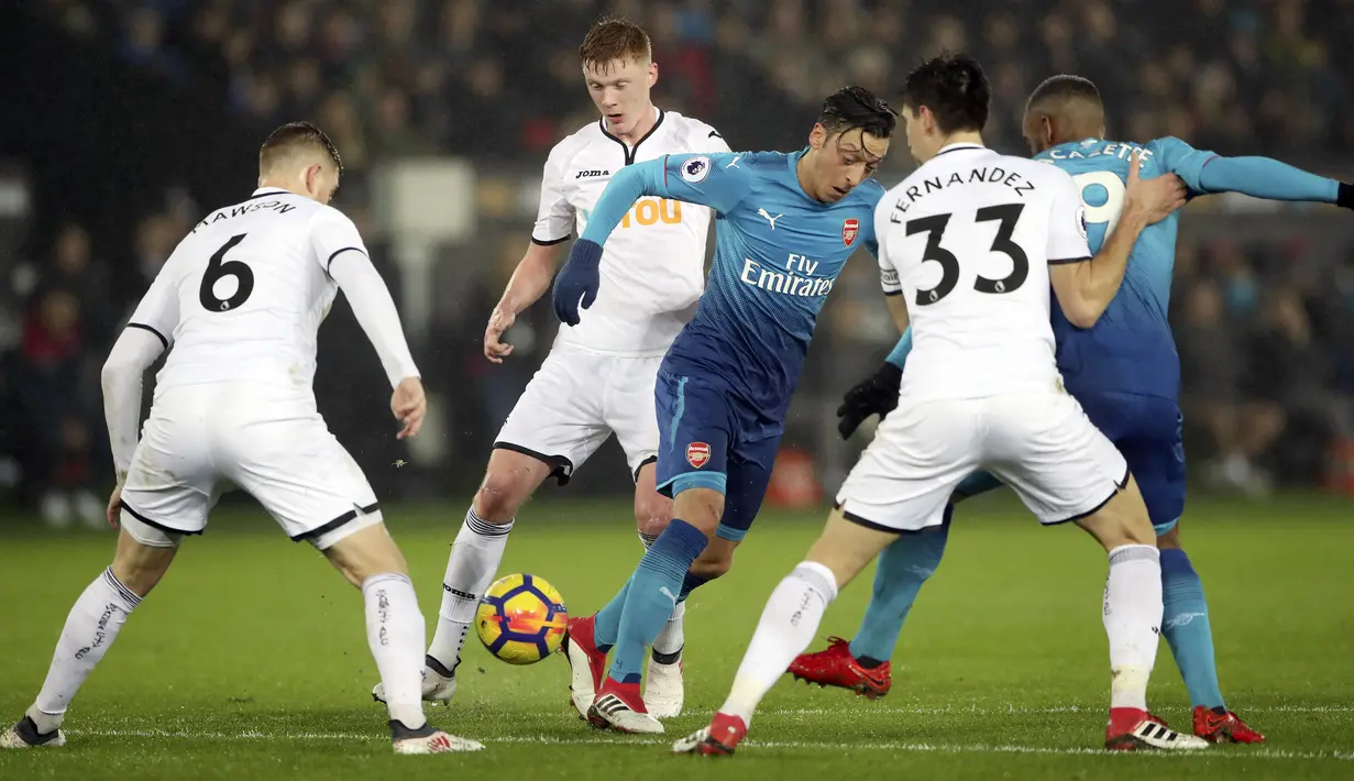 Aksi pemain Arsenal, Mesut Ozil (tengah) menerobos pertahanan Swansea City pada lanjutan Premier League di Liberty Stadium, Swansea, Wales, (30/1/2018). Arsenal kalah 1-3. (Nick Potts/PA via AP)