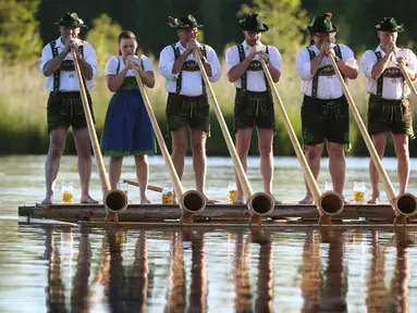 Musisi alphorn, Holdersberger Alp-Traum-Bläser tampil di atas kapal rakit di danau Elbsee, Jerman selatan (11/6). Alphorn ini merupakan alat musik tradisional berupa terompet panjang yang. (AFP PHOTO / DPA / Karl-Josef Hildenbrand / Germany Out)