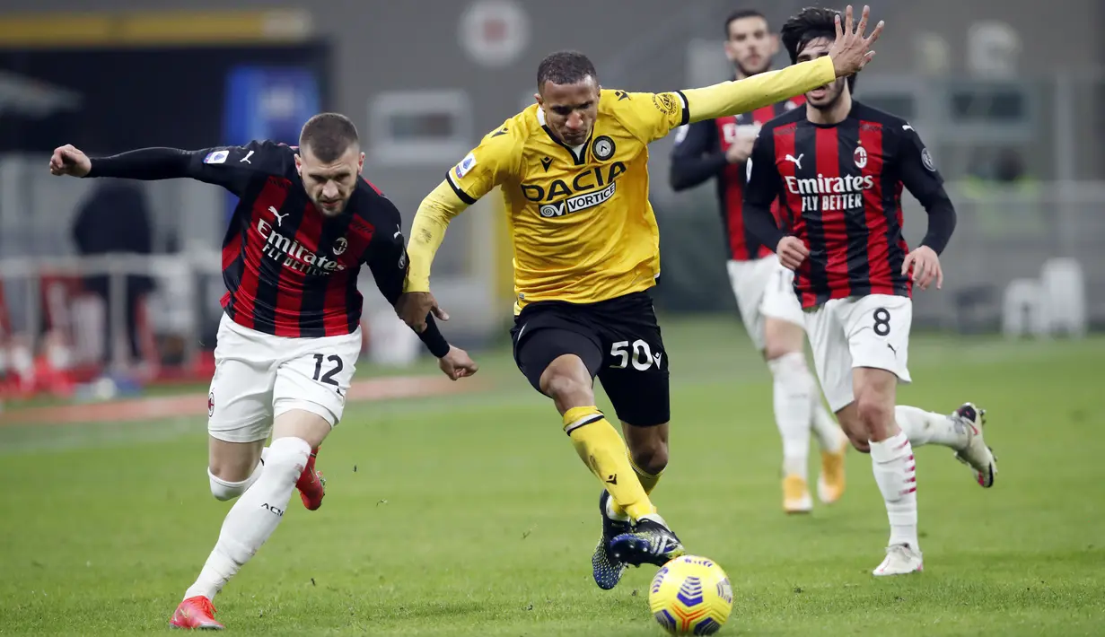 Penyerang AC Milan, Ante Rebic (12) berebut bola dengan bek Udinese, Rodrigo Becão (50) pada pertandigan lanjutan Liga Serie A Italia di stadion San Siro, di Milan, Italia, Kamis (4/3/2021). AC Milan bermain imbang atas Udinese 1-1. (AP Photo/Antonio Calanni)