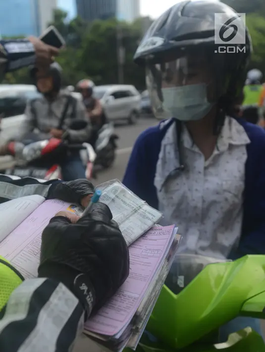 Polantas membuat surat tilang untuk pengendara motor ketika berlangsungnya Operasi Patuh Jaya 2018 di ruas Jalan DI Panjaitan, Jakarta Timur, Jumat (27/4). Razia ini berlangsung selama 14 hari, dari 26 April sampai 5 Mei 2018. (Merdeka.com/Imam Buhori)
