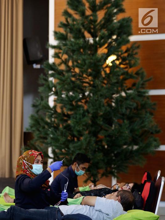 Petugas muslim dari Palang Merah Indonesia (PMI) membantu Jemaat Gereja Protestan Indonesia Bagian Barat (GPIB) dalam donor darah, Jakarta, Minggu (3/12). Kegiatan tersebut diadakan dalam rangkaian acara Natal. (Liputan6.com/JohanTallo)