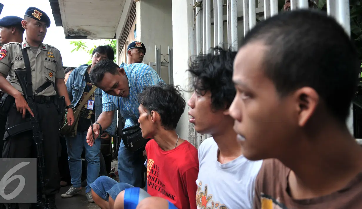 Petugas berbincang dengan warga yang diduga bandar narkoba dan terlibat pengeroyokan di kampung Berlan, Jakarta, Kamis (21/1). Aparat gabungan lakukan penggeledahan dan mencari pelaku tersangka pengeroyokan di kampung Berlan. (Liputan6.com/Yoppy Renato)