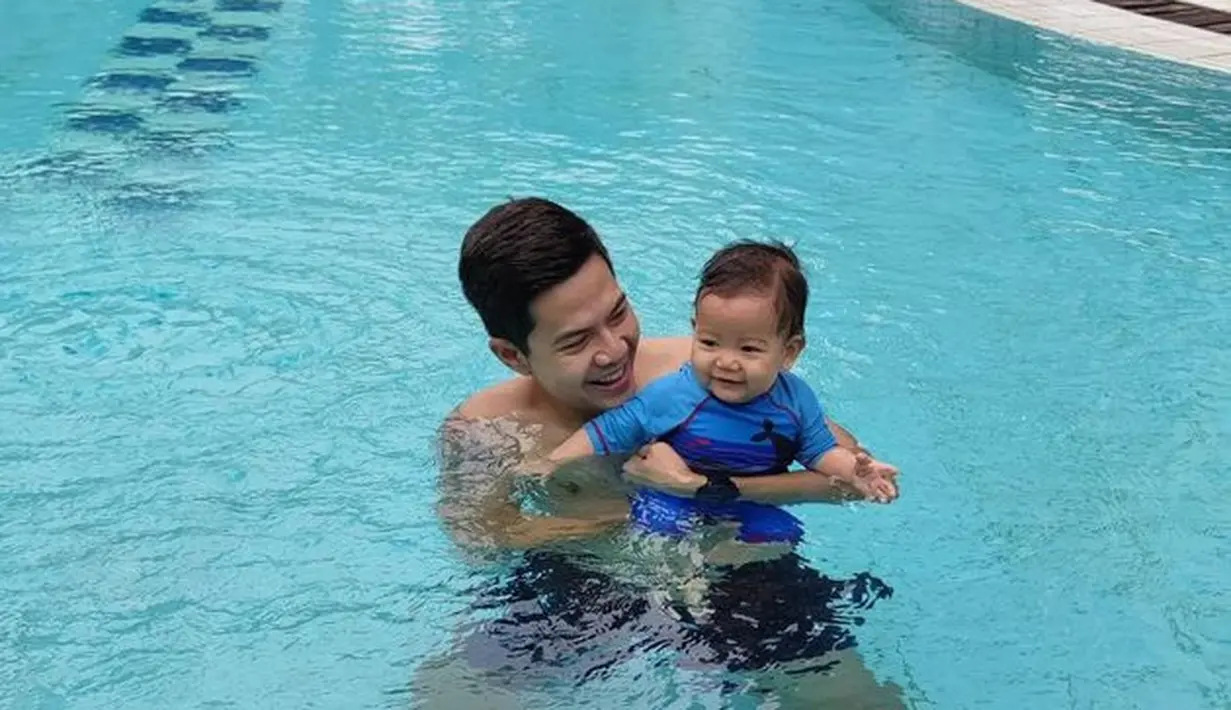 Ardina dan suami sedang menikmati menjadi orang tua. Tak hanya bermain bersama ular, Arie juga ajak si bungsu untuk berenang. (Instagram.com/ardinarasti6)