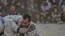Pria Afghanistan bergulat di latar belakang selama tontonan gulat mingguan yang diadakan di arena darurat di taman Chaman-e-Hozori, di Kota Kabul (12/11/2021). (AFP/Hector Retamal)