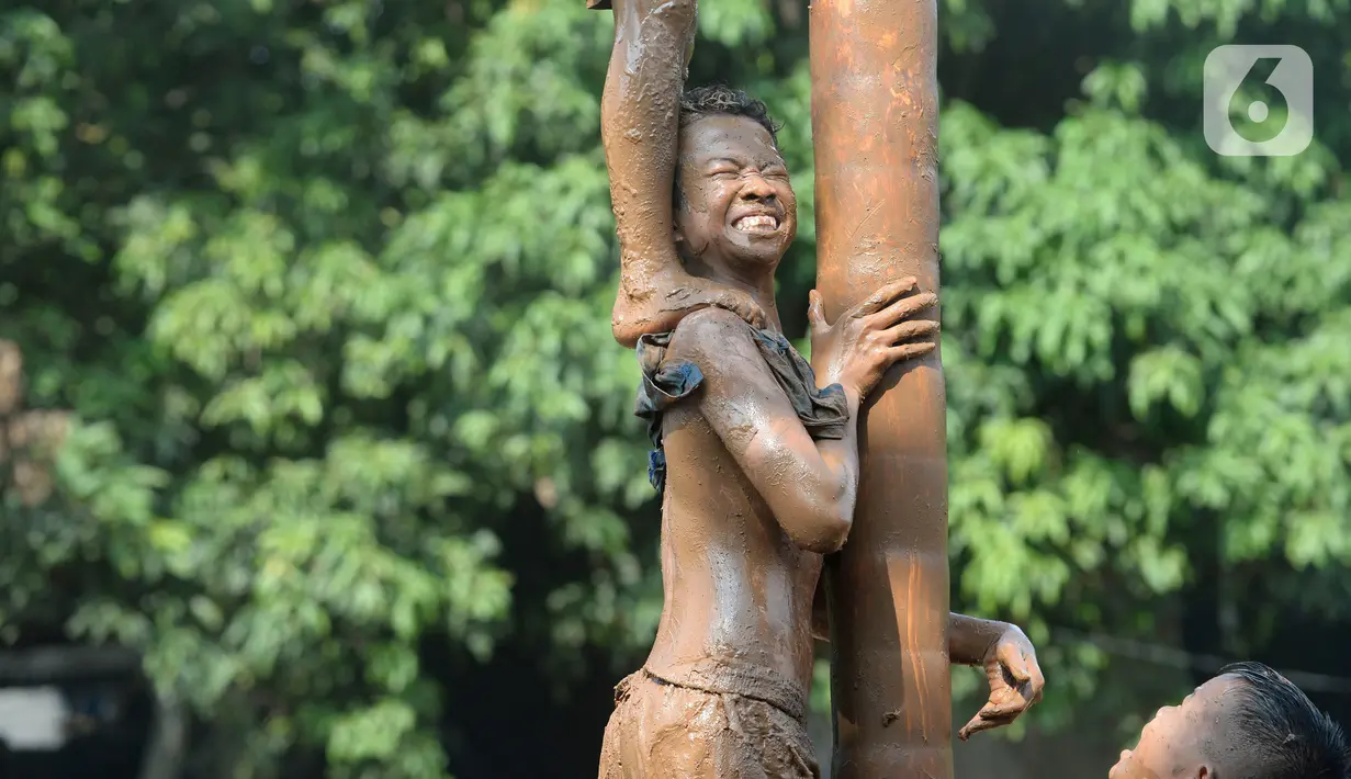 Peserta berusaha menahan temannya untuk menggapai puncak dalam perlombaan panjat pinang di Kampung Bulak, Kelurahan Benda Baru, Pamulang, Tangerang Selatan, Senin (17/8/2020). Lomba di tengah masa pandemi itu guna memeriahkan HUT ke-75 Kemerdekaan RI. (merdeka.com/Dwi Narwoko)