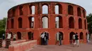 Pengunjung berdiri dekat sebuah struktur di Jantar Mantar, New Delhi, 17 Juli 2018. Bangunan observatorium yang dimiliki India ini terbuat dari batu yang disusun rapi tanpa atap. (AFP/Sajjad HUSSAIN)