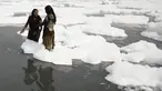 Sejumlah wanita mandi di sungai Yamuna yang tertutup busa limbah sebagai bagian dari ritual untuk festival Chhath Puja yang akan datang di New Delhi, Senin (8/11/2021). Sungai yang sangat dianggap suci oleh umat Hindu India ini dipenuhi lapisan busa karena limbah beracun. (Sajjad HUSSAIN / AFP)