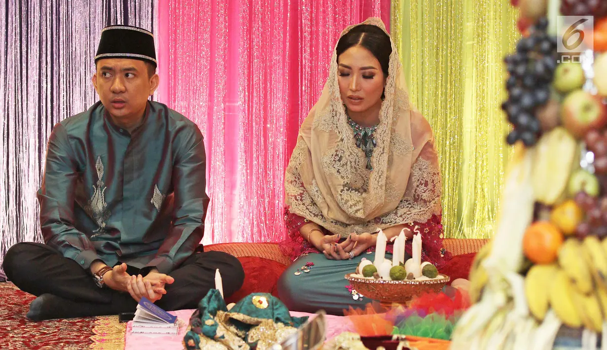 Aktris Ayu Dewi bersama suami Regi Datau berdoa bersama saat prosesi Mohuntingo di kawasan Tebet, Jakarta, Minggu (27/08). Acara potong rombut anak kedua pasangan Ayu Dewi dan Regi Datau digelar secara adat Gorontalo.  (Liputan6.com/Herman Zakharia)