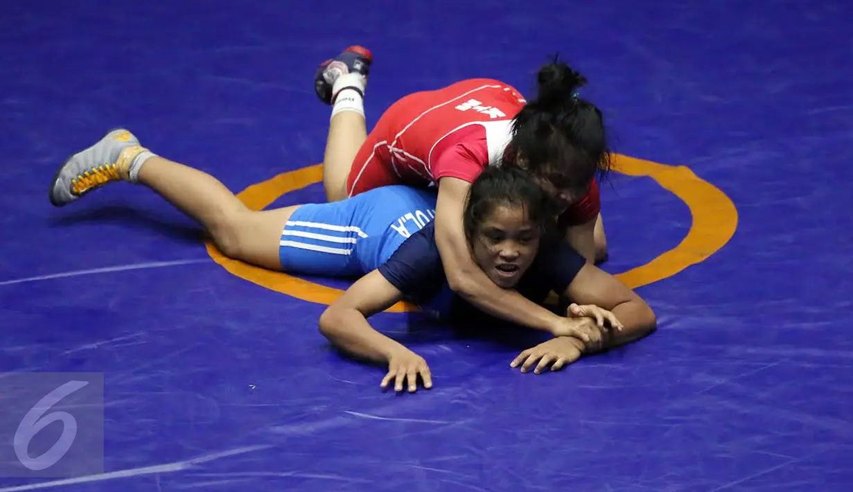 Pegulat putri Kaltim, Inadrah (kostum merah) mengunci gerakan pegulat Sumbar Mardiatul saat final gaya bebas kelas 53 kg putri pada PON XIX di Arena Saparua Sport Park, Bandung, Sabtu (24/9). Inadrah berhasil raih emas. (Liputan6.com/Helmi Fithriansyah)