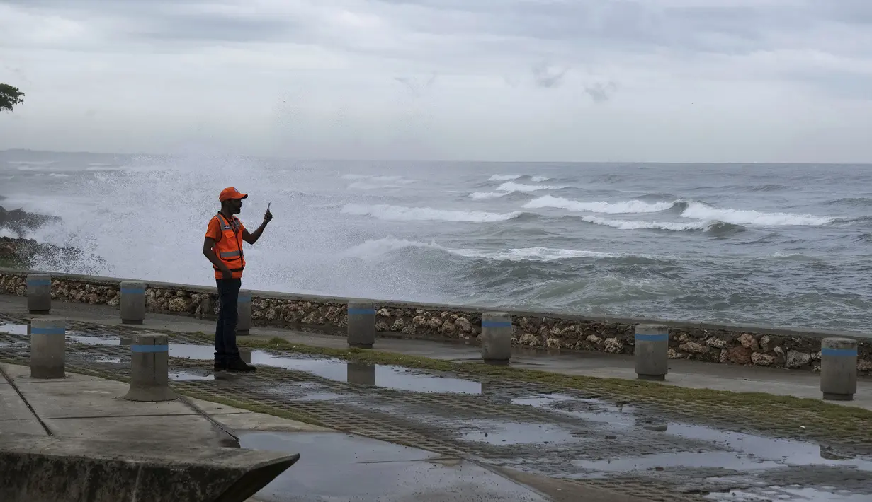 Seorang pria mengambil foto dengan ponselnya saat ombak akibat Badai Tropis Franklin pecah di tembok laut di Santo Domingo, Republik Dominika, Selasa, 22 Agustus 2023. (AP Photo/Ricardo Hernandez)