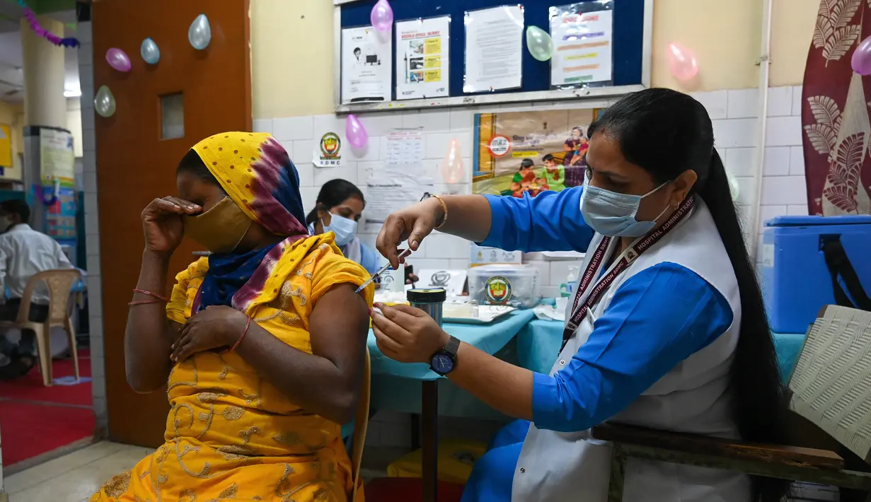 Petugas menyuntikkan vaksin Covid-19 Covaxin kepada seorang wanita di sebuah pusat kesehatan di New Delhi, Kamis (21/10/2021). India pada 21 Oktober mencapai 1 miliar dosis vaksin Covid-19, hanya beberapa bulan setelah lonjakan kasus yang membuat sistem kesehatan hampir runtuh. (Prakash SINGH/AFP)