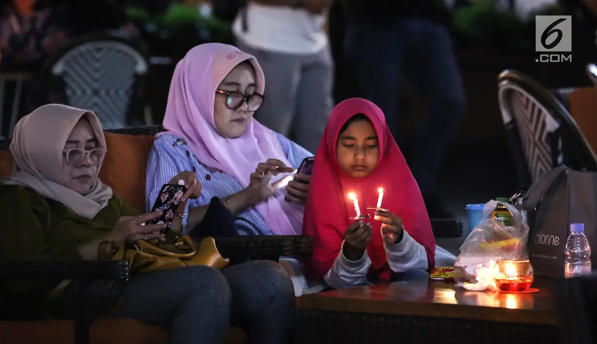 Pengunjung menyalakan lilin mendukung Earth Hour 2019 di Lippo Mall Kemang, Jakarta, Sabtu (30/3). Sebanyak 70 mal yang dikelola Lippo Malls Indonesia serentak memadamkan lampu eksterior dan 50% lampu penerangan di dalam gedung dari pukul 20:30 - 21:30 waktu setempat. (Liputan6.com/Fery Pradolo)