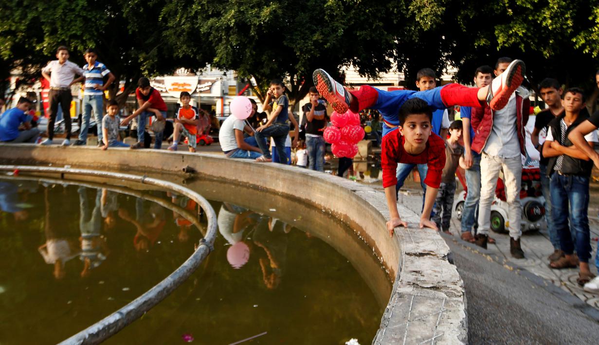 Warga melihat Mohammed al Sheikh meliukkan tubuh di Gaza, Kamis (2/6). Sebelumnya, remaja 12 tahun itu pernah tampil di ajang pencarian bakat Arabs Got Talent Show di Lebanon. Sayang, kemahirannya tak mampu membuat orang terkesan. (REUTERS/Mohammed Salem)