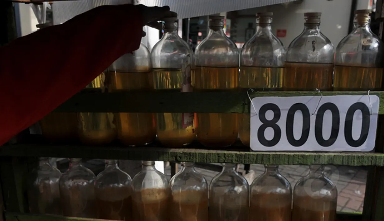 Seorang pedagang bensin eceran jenis premium merapikan  jualannya di kawasan Petamburan, Jakarta, Senin (2/3/2015). Pemerintah kembali menaikkan harga BBM jenis Premium sebesar Rp 200 per liter per 1 Maret 2015 pukul 00.00 WIB. (Liputan6.com/Johan Tallo)