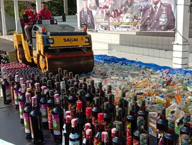 Petugas dengan alat berat menghancurkan botol minuman keras (miras) saat pemusnahan Miras dan barang bukti narkotika di Mapolrestabes Semarang, Jumat (20/12/2019). Pemusnahan barang bukti narkoba berupa sabu, inex dan pil koplo serta 5450 botol dan 140 liter ciu. (Liputan6.com/Gholib)