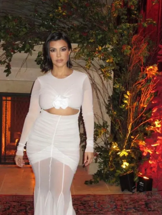 Kourtney Kardashian Barker yang baru menikah masih mengenakan pakaian putih. Ia tampil menawan dengan gaun putih ruched yang dihiasi bunga di dada. @krisjenner.