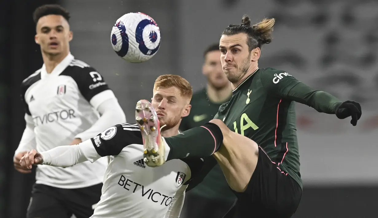 Gelandang Fullham, Harrison Reed berebut bola dengan penyerang Tottenham Hotspur, Gareth Bale pada pekan ke-27 Liga Inggris di Craven Cottage, Jumat (5/3/2021) dini hari WIB. Tottenham Hotspur unggul 1-0 atas Fullham lewat gol bunuh diri Tosin Adarabioyo. (Neil Hall/Pool via AP)
