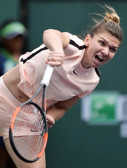 Petenis putri nomor satu dunia, Simona Halep melakukan servis ke arah petenis Cina, Wang Qiang pada turnamen BNP Paribas Terbuka di Indian Wells, Selasa (13/3). Halep mengalahkan pendatang baru Wang Qiang 7-5 6-1. (Kevork Djansezian/Getty Images/AFP)