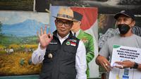 Gubernur Jawa Barat Ridwan Kamil menyerahkan uang hasil penjualan lukisan milik penjual lukisan di Jalan Braga, Kota Bandung, yang ia bantu penjualannya lewat NFT Opensea, Selasa (25/1/2022). (Foto: Biro Adpim Jabar)