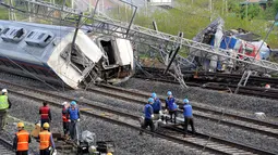 Petugas berusaha mengevakuasi sebuah kereta penumpang yang tergelincir di kota pelabuhan selatan Yeosu, Korea Selatan, Jumat (22/4). Akibat kecelakaan itu masinis tewas, sementara delapan penumpang mengalami luka-luka. (Hwang Hee-kyu/News1 via REUTERS)