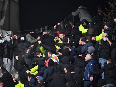 Petugas keamanan turun tangan di tribun penonton ketika para pendukung bentrok pada pertandingan 64 besar Piala Prancis antara Paris FC dan Olympique Lyon di stadion Charlety, Paris,  Jumat (17/12/2021). Laga pun dibatalkan menyusul kerusuhan penonton tersebut. (Bertrand GUAY/AFP)