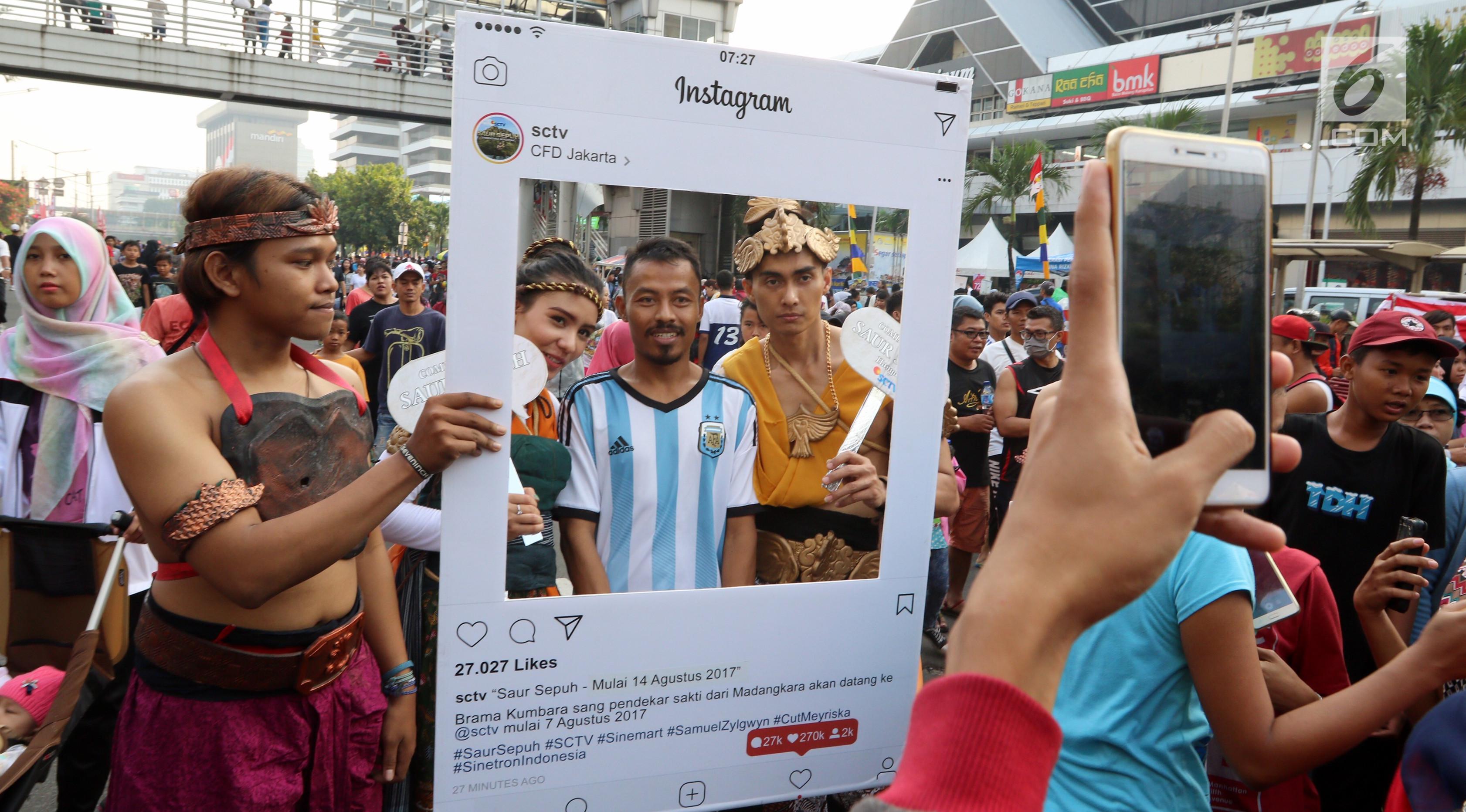 Warga berswafoto bersama karakter Brama Kumbara dan Mantili saat pawai untuk mempromosikan sinetron laga Saur Sepuh The Series di area Car Free Day, Jakarta, Minggu (6/8). (Liputan6.com/Fery Pradolo)