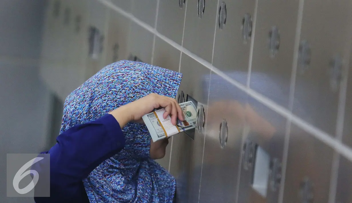 Petugas memasukan uang pecahan US$100 ke brankas di Jakarta, Jumat (9/10/2015). Nilai tukar rupiah terhadap dolar AS pada perdagangan akhir pekan ini, Jumat (9/10/2015) mengalami penguatan, bahkan bergerak ke level Rp 13.400. (Liputan6.com/Angga Yuniar)