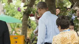 Barack Obama menunggu kelapa yang sedang di buka di sepanjang Sungai Mekong di Luang Prabang, Laos (7/9). Obama menjadi presiden AS pertama yang mengunjungi Laos dan mendarat di Vientiane akhir pada 5 September. (AFP PHOTO/SAUL Loeb)