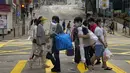Pembeli yang mengenakan masker berjalan di seberang jalan di Hong Kong, Minggu (13/3/2022). Pemimpin Hong Kong Carrie Lam mengatakan infeksi Covid-19 di kota itu belum melewati puncaknya meskipun jumlah kasus harian baru-baru ini sedikit menurun. (AP Photo/Kin Cheung)