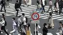 Orang-orang yang memakai masker berjalan di sepanjang penyeberangan pejalan kaki di distrik Shibuya, Tokyo, Kamis (30/9/2021). Jepang akan mencabut keadaan darurat COVID-19 di semua wilayah pada akhir September. (AP Photo/Eugene Hoshiko)