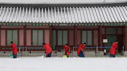Sejumlah wanita mengenakan pakaian tradisional Korea "Hanbok" membersihkan salju di Istana Gyeongbok di Seoul, Korea Selatan (15/2). Istana Gyeongbok aslinya didirikan tahun 1394 oleh Jeong do jeon, seorang arsitek.  (AP Photo/Ahn Young-joon)