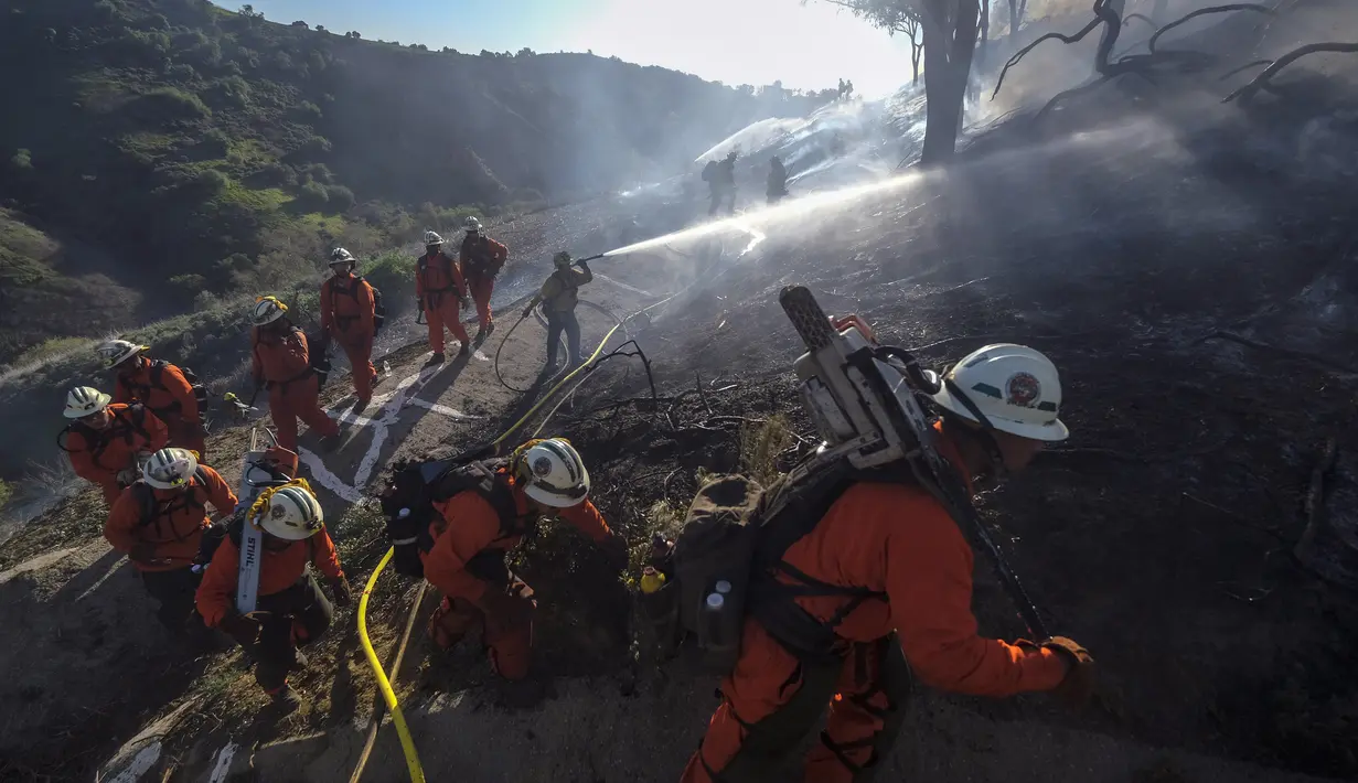 Petugas pemadam kebakaran bekerja pada kebakaran hutan di dekat rumah di Laguna Beach, California, Kamis (10/2/2022). Setidaknya dua rumah hancur dalam kebakaran semak yang menghitamkan sekitar empat hektar di daerah Whittier. (AP Photo/Ringo H.W. Chiu)