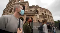Orang-orang memakai masker untuk mencegah penyebaran COVID-19 saat mereka berjalan-jalan di dekat Colosseum, di Roma pada Sabtu (3/10/2020). Masker wajah harus dipakai setiap saat di luar rumah di ibu kota Italia Roma dan wilayah sekitar Lazio mulai Sabtu, 3 Oktober. (AP Photo/Andrew Medichini)