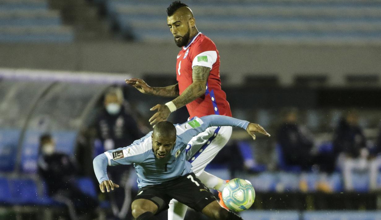 Gelandang Uruguay, Nicolas de la Cruz, berebut bola dengan gelandang Chile, Arturo Vidal, pada laga kualifikasi Piala Dunia 2020 zona Amerika Selatan di Estadio Centenario, Jumat (9/10/2020) pagi WIB. Uruguay menang 2-1 atas Chile. (AFP/Ernesto Ryan/pool)