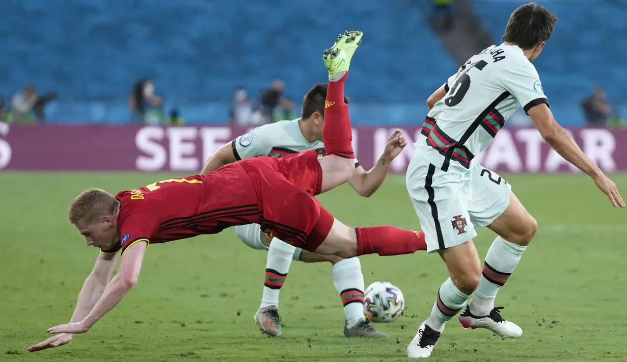 Gelandang timnas Belgia, Kevin De Bruyne (kiri) ditantang pemain Portugal Raphael Guerreiro dan Joao Palhinha pada babak 16 besar Euro 2020 di Estadio La Cartuja, Sevilla, Senin (28/6/2021) dini hari WIB. Belgia mendepak juara bertahan Portugal berkat kemenangan 1-0. (THANASSIS STAVRAKIS/POOL/AFP)