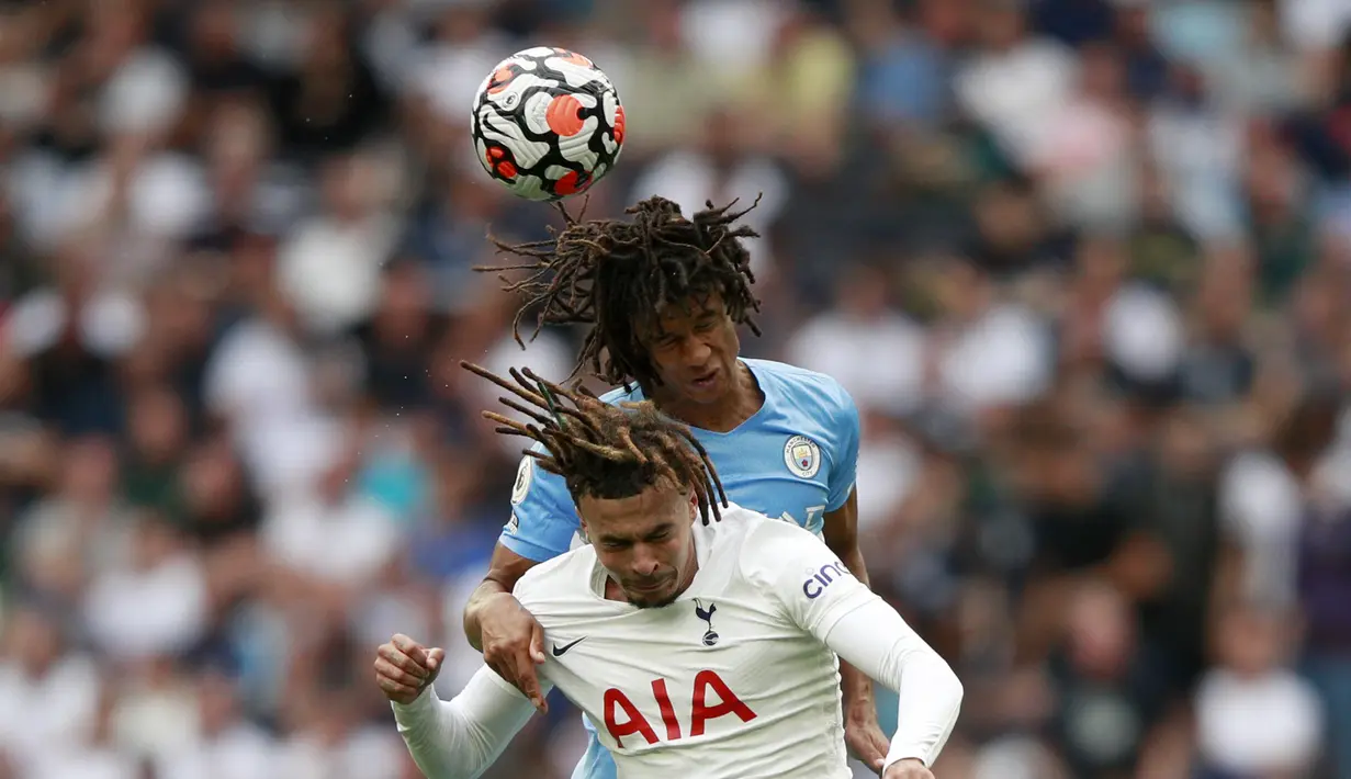 Bek Manchester City, Nathan Ake berebut bola udara dengan gelandang Tottenham Hotspur, Dele Alli pada pertandingan Liga Inggris di Stadion Tottenham Hotspur di London, Minggu (15/8/2021). Tottenham menang atas City lewat gol tunggal Son. (AP Photo/Ian Walton)